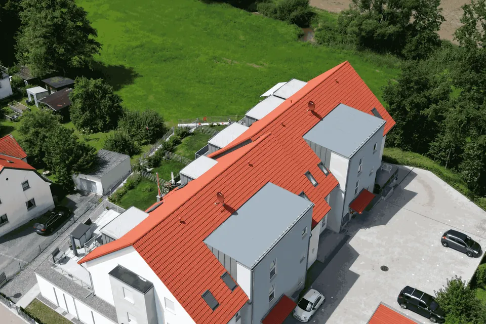 Fertiggestelltes Mehrfamilienhaus mit verputzter Fassade aus der Drohnenperspektive
