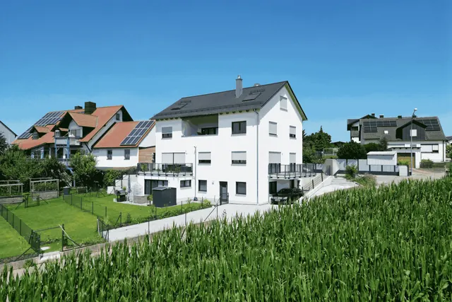 Weißes Mehrfamilienhaus mit Balkonen am Ortsrand