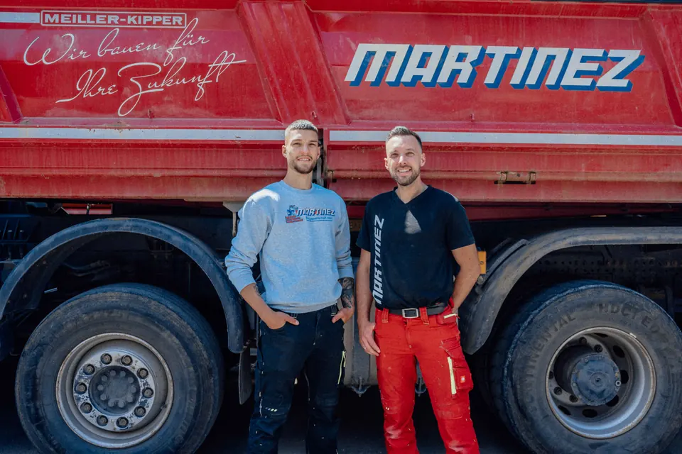 Marco und Domingo Martinez vor dem roten Martinez-Kipper — das Team der Martinez Baugesellschaft